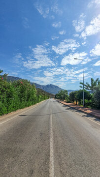 Sunny and cloudy road in tropic place with trees and mountain