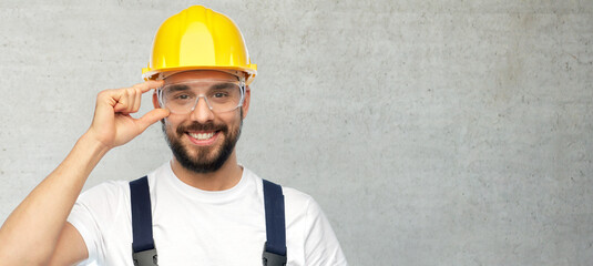 profession, construction and building concept - happy smiling male worker or builder in yellow...