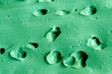 Green cosmetic clay (kelp facial mask, face cream, spirulina body wrap) texture close up, selective focus. Abstract background.