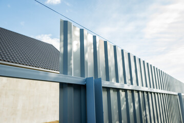 Fototapeta na wymiar Installation of gray fence from metal profile.