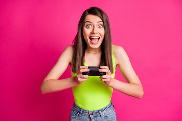 Photo of positive young girl wear casual outfit play video game hold joystick isolated over pink color background