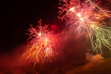 Falling and red - orange fireworks above a illuminated church and against the backdrop of the night sky, Vittorio Veneto, Italy