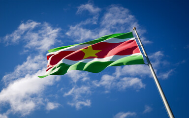 Beautiful national state flag of Suriname fluttering at sky background. Low angle close-up Suriname