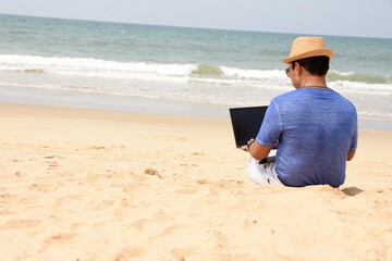 A man using his laptop and working from sea beach, during this pandemic where work from home is part of life , now people can work from anywhere and at the same time have a feel of vacation
