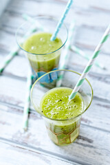  Green smoothie topped with chia seeds on bright wooden background. Close up.