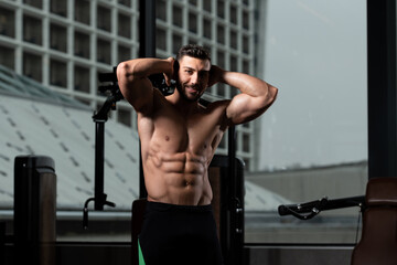 Fototapeta na wymiar Handsome Muscular Man Flexing Muscles in Gym