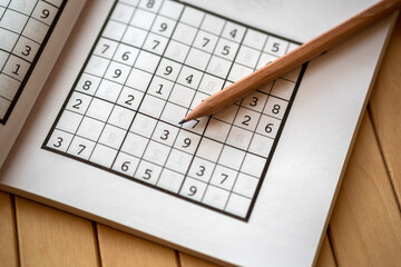 sudoku (crossword) puzzle and pencil. Selective focus.