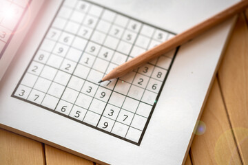 sudoku (crossword) puzzle and pencil. Selective focus.