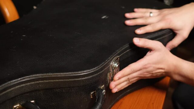 Close frame of male hands closing guitar case   