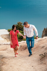 Young married couple admires the sea or ocean at edge of a rocky cliff. Family photoshoot on background of crag