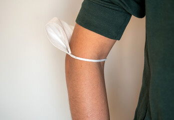 Coronavirus concept. Wrong use of medical face mask against covid-19. Man attaches a surgical mask to his arm or elbow.  unsafe use of medical mask against corona.