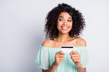 Photo portrait of dreamy woman holding plastic card in two hands looking at blank space isolated on...