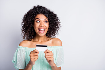 Photo portrait of ecstatic woman holding debit card in two hands looking at blank space isolated on white colored background