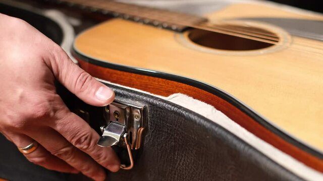 Close frame of male hands opening guitar case  