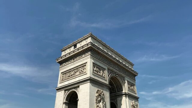 Footage of famous landmark called "Arc de Triomphe" in Paris. It is a sunny summer day. Camera pans left.