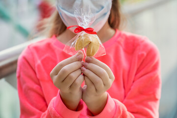 A child in a medical mask holds a fortune cookie in his hands. Pandemic with coronavirus COVID-19...