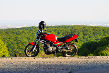 Obraz na płótnie Canvas Ein rotes sportliches Motorrad auf Hügel am Rand von Wien an einem sonnigen Tag