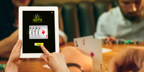 Online gambling, casino concept. Hand holding device with lottery, casino cover. Playing dips and cards on table on the background. Poker, bookmaking, gaming, modern technologies, business and finance