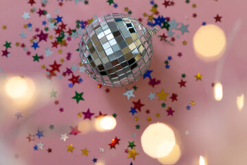 silver disco ball reflecting lights on pink background, greeting card with sparkles template, empty space for text

