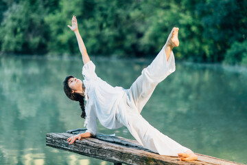 Yoga by the Lake – Young woman doing yoga exercise plank star pose
