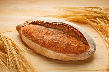 Hot fresh bread on a wooden table with wheat ears.