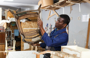 Portrait of craftsman restoring old chair in woodwork studio