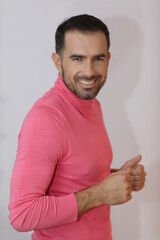 Portret mężczyzny w różowym sweterku. Biały uśmiech bruneta. 