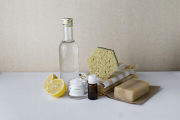 Natural cleaning products vinegar, lemon, soda, linen towel, natural soap, sponge are spread out on the table on a light background