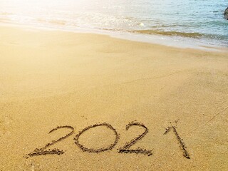 Welcome new year 2021 Write on the sand by the sea, near the sunset.