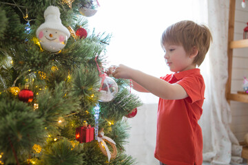 Little boy decorating the Christmas tree at home