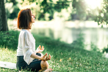 Young Woman Practicing Meditation near Water in the Nature
