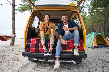 Friends drinking tea on the trunk of a car