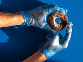Male hand holding donut with cream. Doctor urologist in medical gloves doing prostate massage....