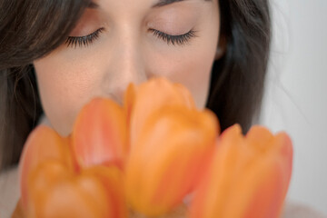 Stylish young woman smelling tulips with closed eyes.
