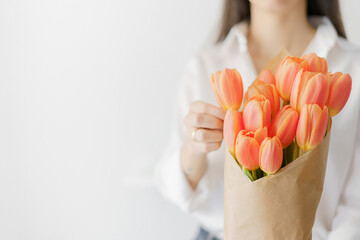 woman holding with the left hand a bouquet of orange tulips