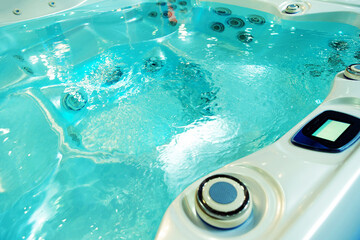Jacuzzi with turquoise clear water. A fragment of a swimming pool with a control panel and massage...