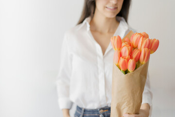 woman holding with her left hand a bouquet of orange tulips