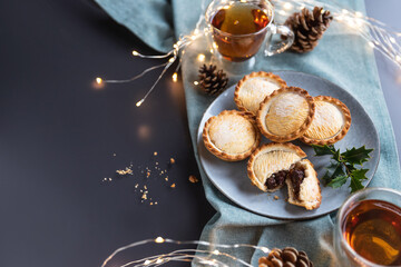 Obraz na płótnie Canvas mince pies on a plate served with black tea shot from above with copy space. A mince pie is a traditional Christmas sweet pie, filled with a mixture of dried fruits and spices.