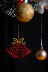 Christmas ornaments, highlighted by Santa Claus and Christmas bell between red and gold balls on black background.
