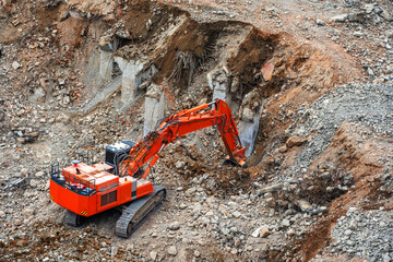 Excavator works on with stone debris after the demolition of a dilapidated building
