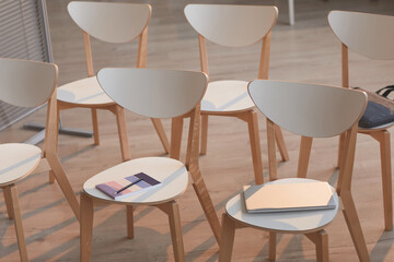 Close-up of wooden empty chairs with notepads on them preparing for business meeting at board room
