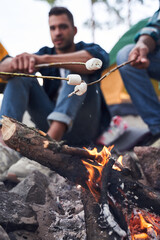 Guys frying marshmallows at the forest