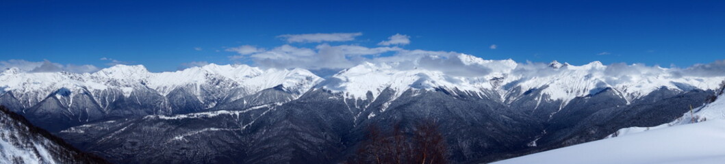 Fototapeta na wymiar Winter landscape in the mountains. Snow-capped mountain peaks, blue sky, ski slopes.