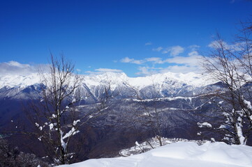 Fototapeta na wymiar Winter landscape in the mountains. Snow-capped mountain peaks, blue sky, ski slopes.