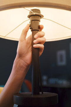 Woman Turning On A Table Lamp