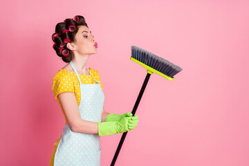 Portrait of nice attractive brown-haired maid holding in hand broom sending air blow kiss hygiene...