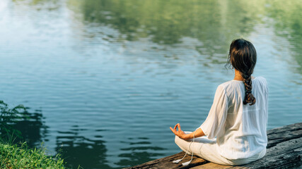 Yoga Retreat. Peaceful Young Woman Sitting in Lotus Position and Meditating by the Lake