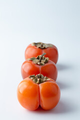 Persimmon fruits lie in a row on a white background.