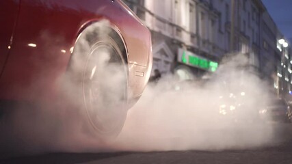 Car burns rubber off its tires in preparation for the race. Footage. Slow motion video of sport vehicles right back wheel the tire burns against the asphalt with smoke
