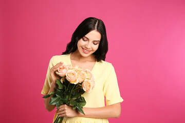 Portrait of smiling woman with beautiful bouquet on pink background